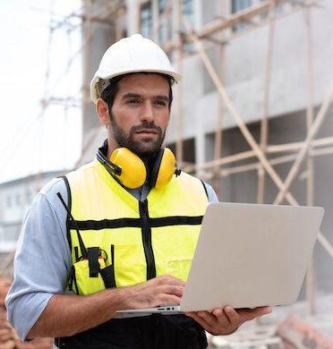 Worker in a construction site. Architecture engineering holding a laptop on building site checking plans. Successful engineer or architect, Joyous businessman. Construction worker.