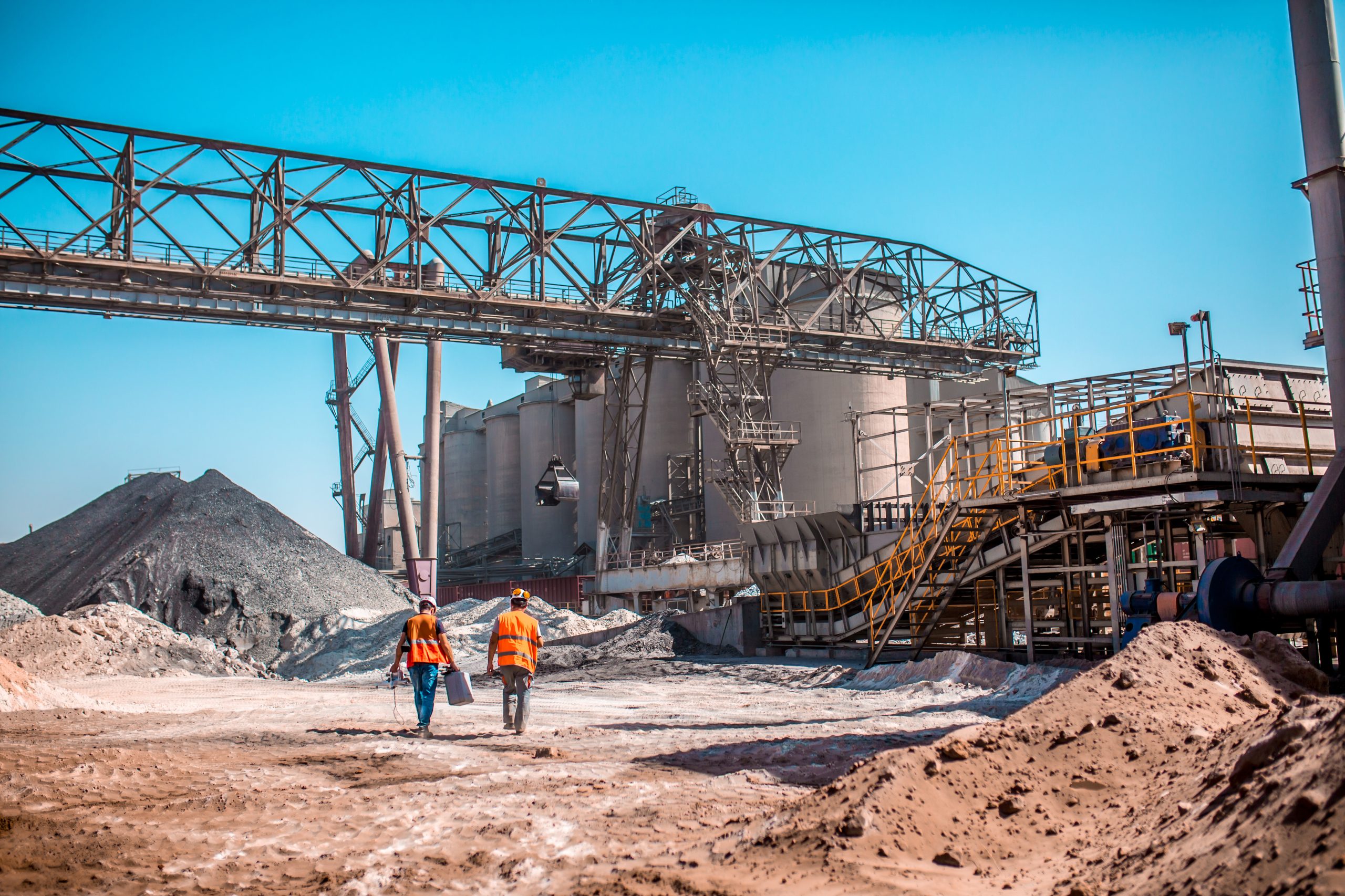 Two-people-walking-across-aggregate-yard-at-concrete-plant