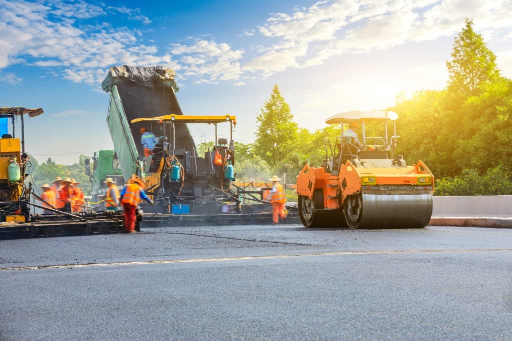 asphalt crew paving a highway with a truck, paver, roller and laborers