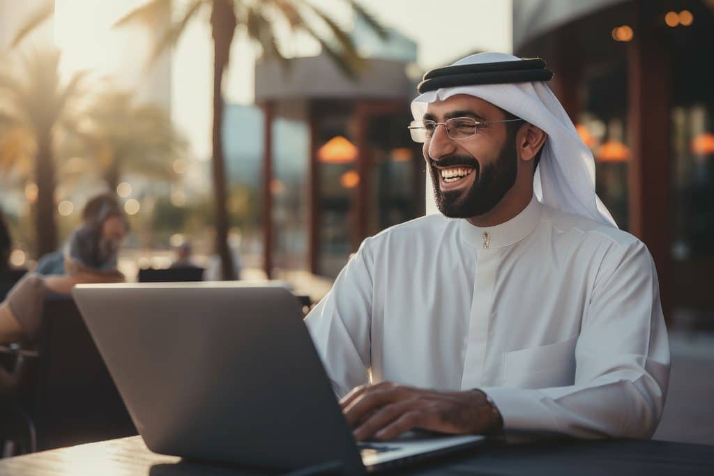 middlee eastern man in traditional dress enjoying technology on his laptop